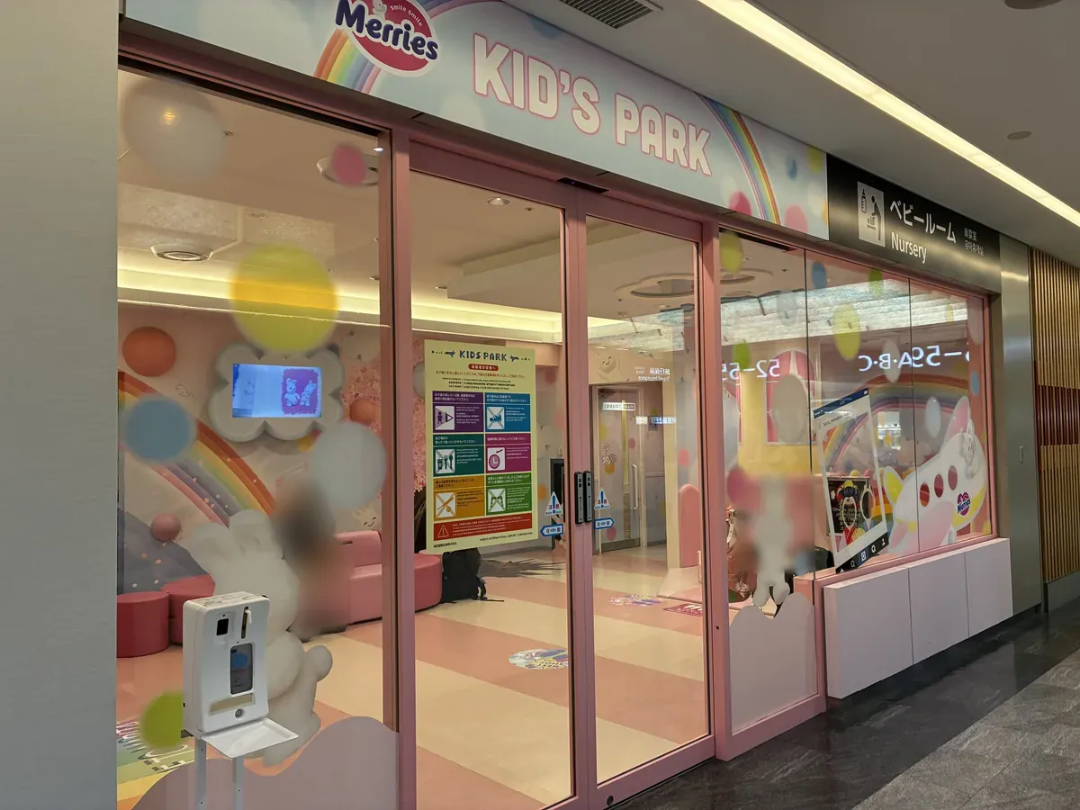 「Merries KID'S PARK」と書かれたピンク色の入口。ガラス越しにカラフルな遊具や装飾が見え、ベビー休憩室の案内も表示されている。