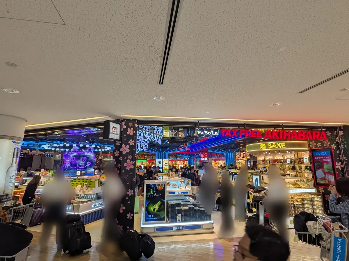 空港内の免税店エリア「Fa-So-La Tax FREE AKIHABARA」の様子。カラフルな照明に照らされた店内には様々な商品が並び、多くの買い物客で賑わっている。