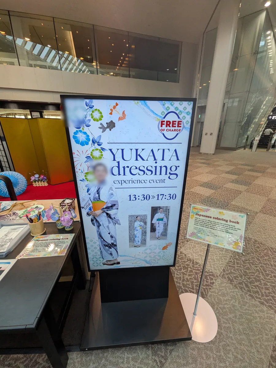 空港ターミナル内で開催されている「YUKATA dressing experience event」の案内板。浴衣を着た人物のイメージ写真とイベントの開催時間が表示されている。