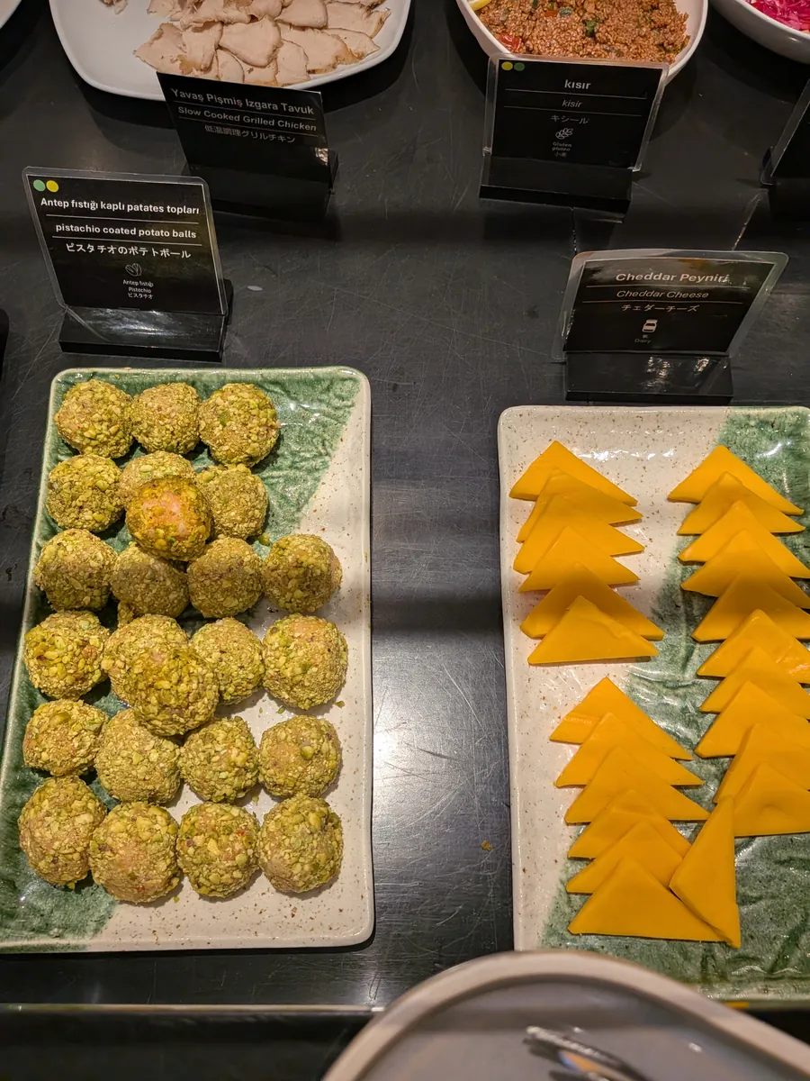 ビュッフェカウンターの料理。ピスタチオをまぶしたポテトボールと、三角形にカットされたチェダーチーズが皿に盛られている。