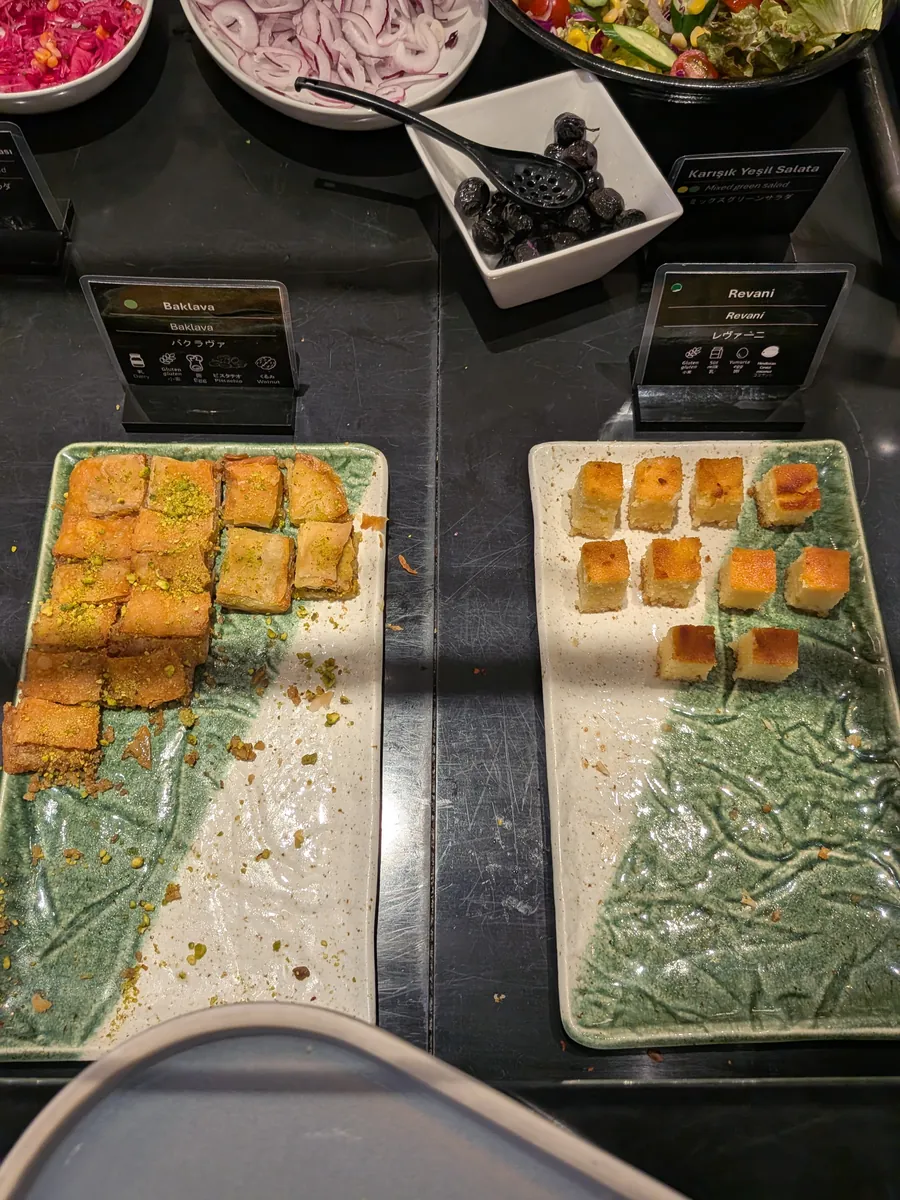 ビュッフェカウンターに並べられたトルコの伝統菓子。シロップ漬けのバクラヴァとレヴァニが、それぞれ特徴的な模様の皿に盛られている。