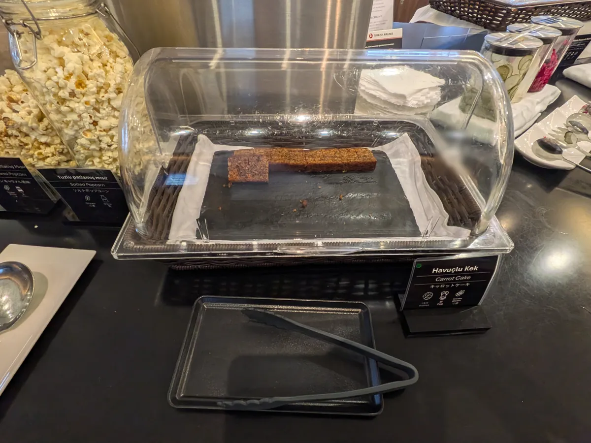 ビュッフェカウンターのデザート。透明なケースに入ったキャロットケーキと、大きな瓶にたっぷり入ったポップコーンが並んでいる。