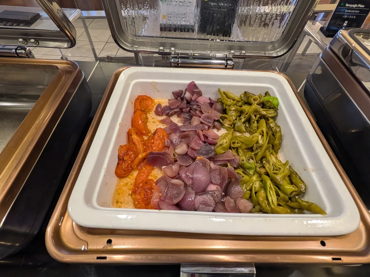 ビュッフェカウンターの温菜コーナー。ローストトマト、赤玉ねぎ、ピーマンなどの温野菜が、保温器に入って提供されている。