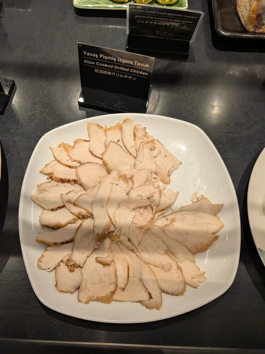 ビュッフェカウンターに盛られた低温調理グリルチキン。薄くスライスされており、しっとりとした食感が想像される。