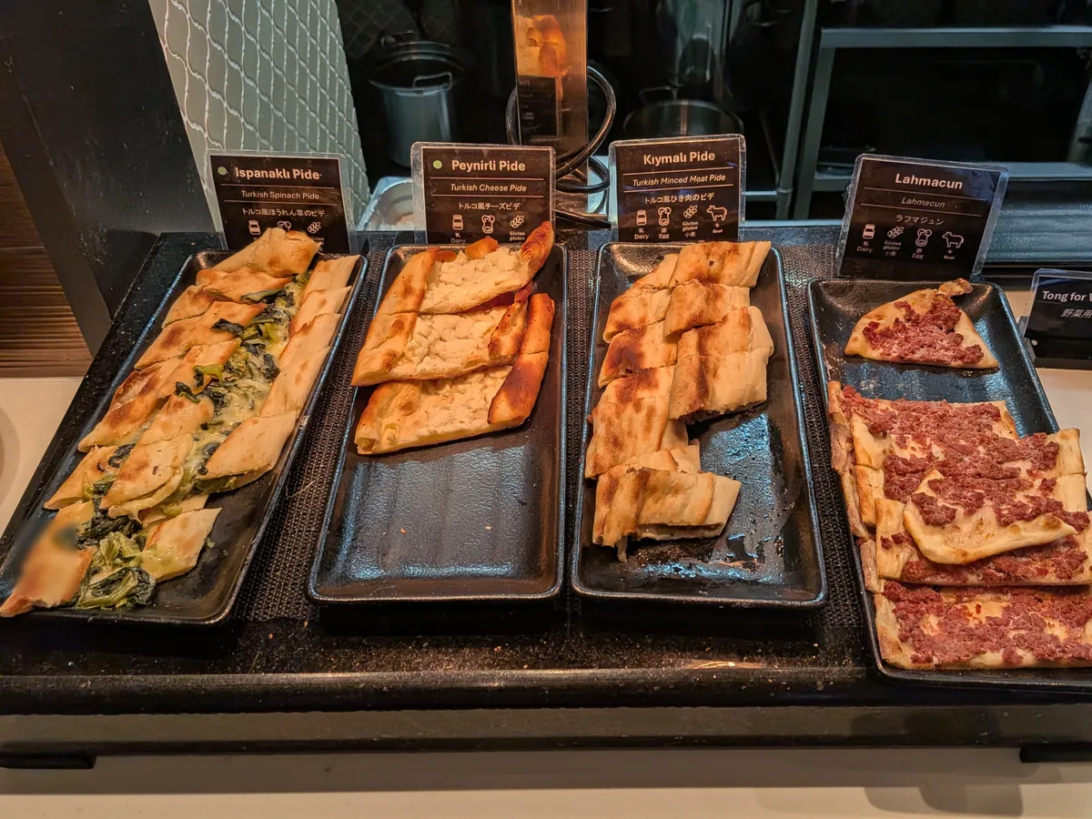 ビュッフェカウンターに並べられたトルコ風ピザ。ほうれん草のピデ、チーズピデ、ひき肉ピデ、ラフマジュンなど数種類が提供されている。