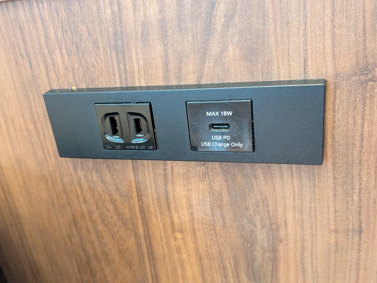 木目調の壁に取り付けられた充電コンセント。通常のコンセントに加え、USB PD対応のUSB充電ポートも備えられている。