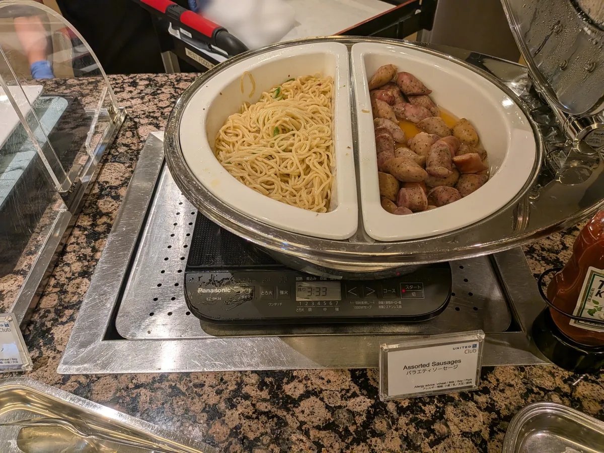 ホットミールコーナーのパスタとバラエティソーセージ。保温器に温かく保たれている。