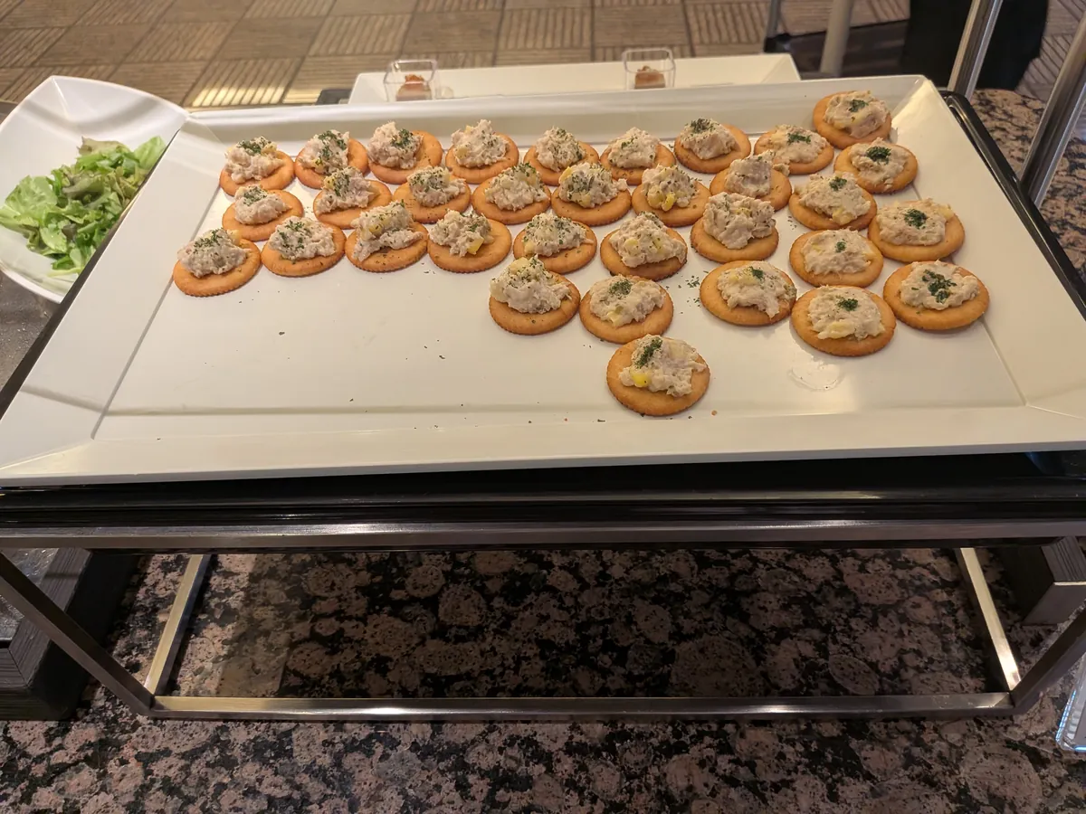 クラッカーに乗せられたツナサラダ風の軽食。白い大きなトレイにきれいに並べられている。