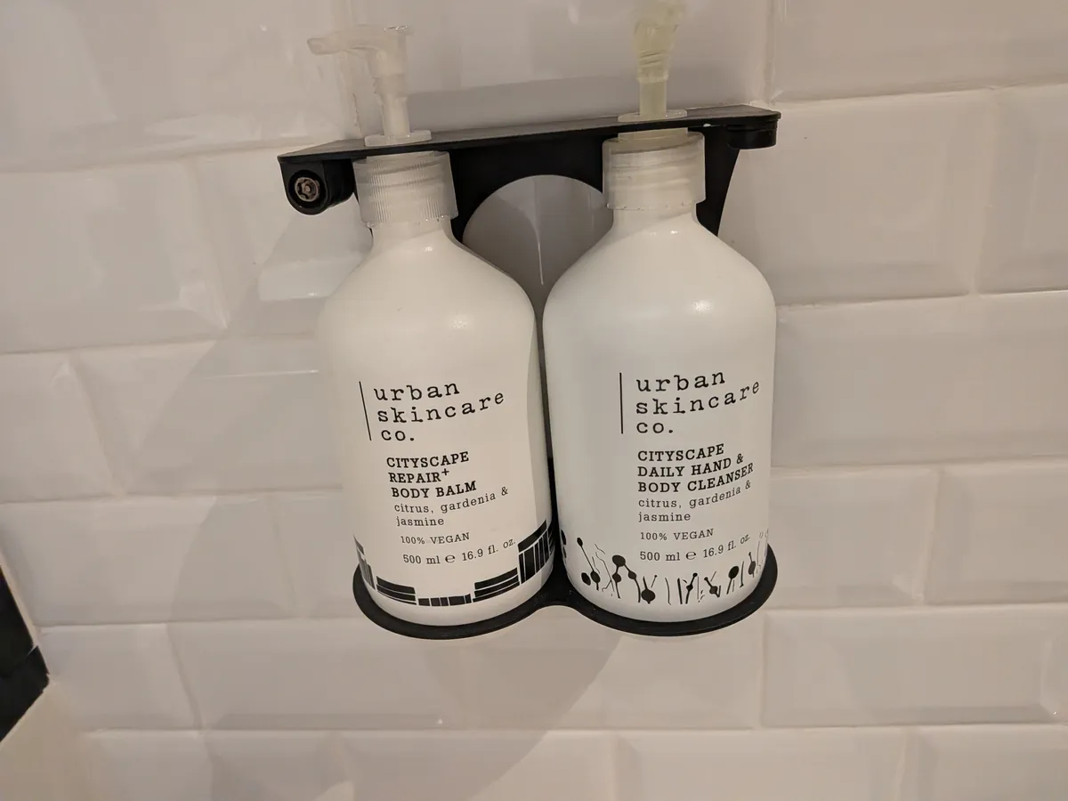 シャワーブースの壁付けアメニティ。urban skincare co.のボディバームとハンド＆ボディクレンザー