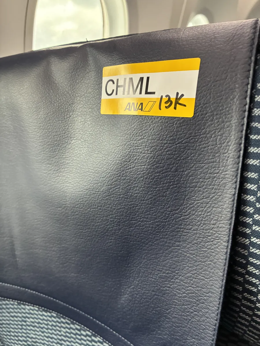 ANA機内の座席背面に貼られた黄色いシール。CHML(お子様向けのお食事)と座席番号が手書きされている