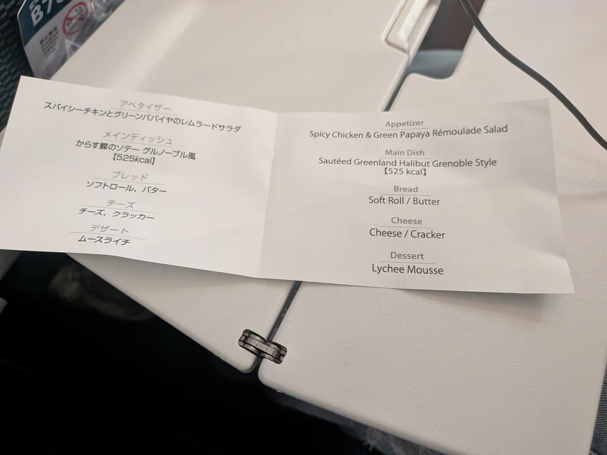 ANA有料機内食のメニューカード。アペタイザー、メインのからす鰈のソテー グルノーブル風、チーズ、デザートのムースライチが日英併記で書かれている