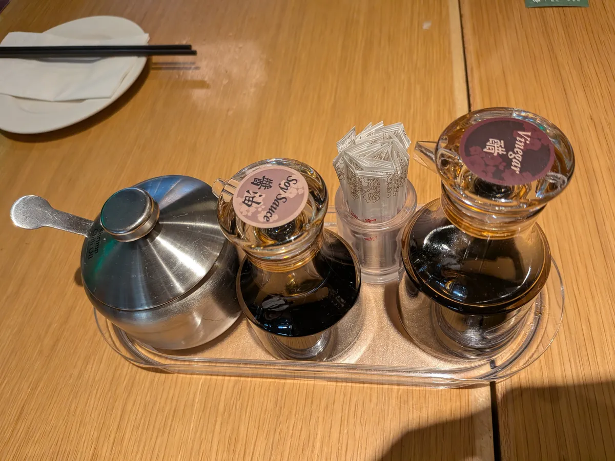 卓上の調味料セット。醤油、黒酢、ラー油の容器がトレイに並ぶ