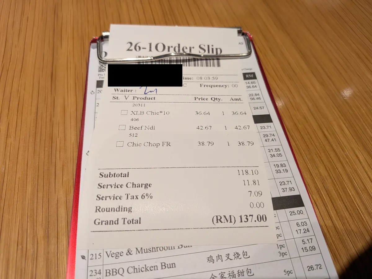 会計のオーダースリップ。小籠包・牛肉麺・炒飯の3品と合計RM137.00の内訳(伝票番号は黒塗り)