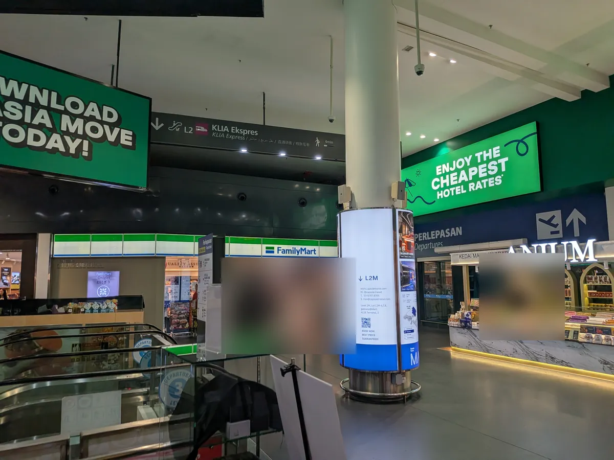 gateway@klia2の館内。ファミリーマートとKLIA Ekspresの案内サイン、カプセルホテルの広告