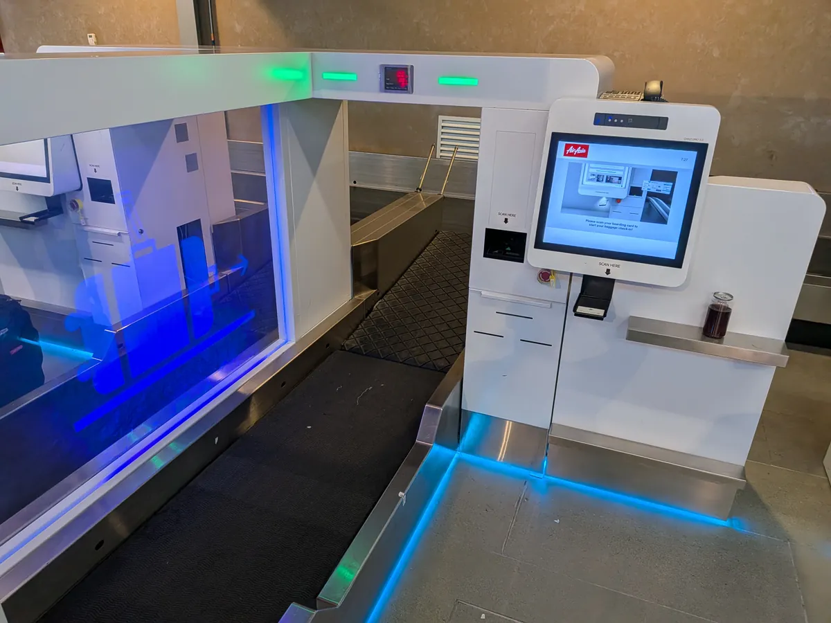 エアアジアのセルフバゲージドロップ機。青くライトアップされたベルトコンベアとタッチパネル