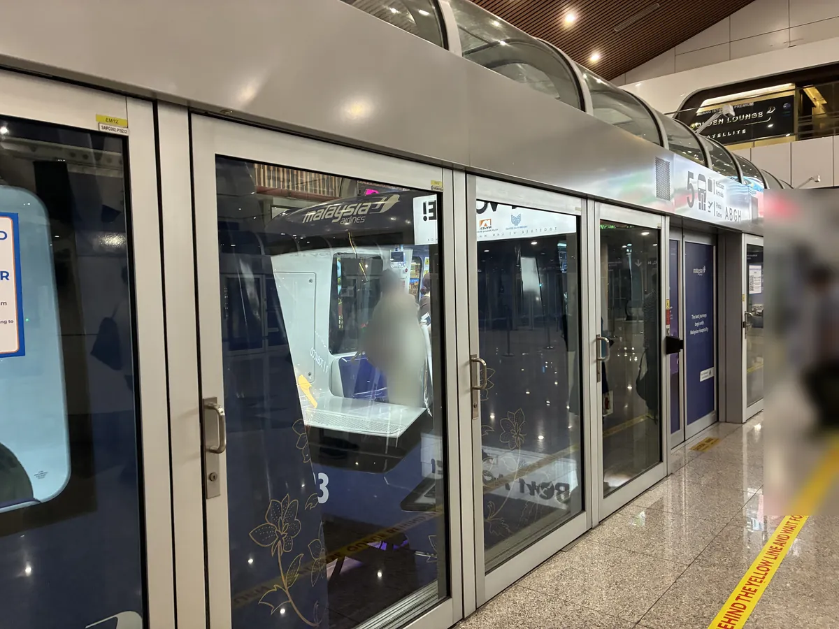 エアロトレインのホームドアが並ぶ通路。黄色い乗車位置の線と免税店の看板が見える
