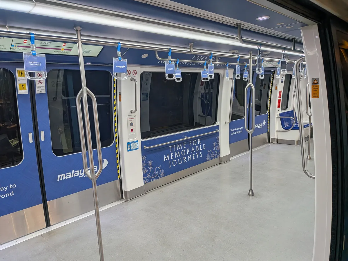 エアロトレインの車内。青い内装と吊り革が並ぶ立ち乗り主体の空間