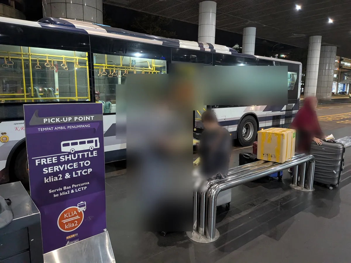無料シャトルバスの乗り場。紫の看板に「FREE SHUTTLE SERVICE TO klia2 & LTCP」と書かれている