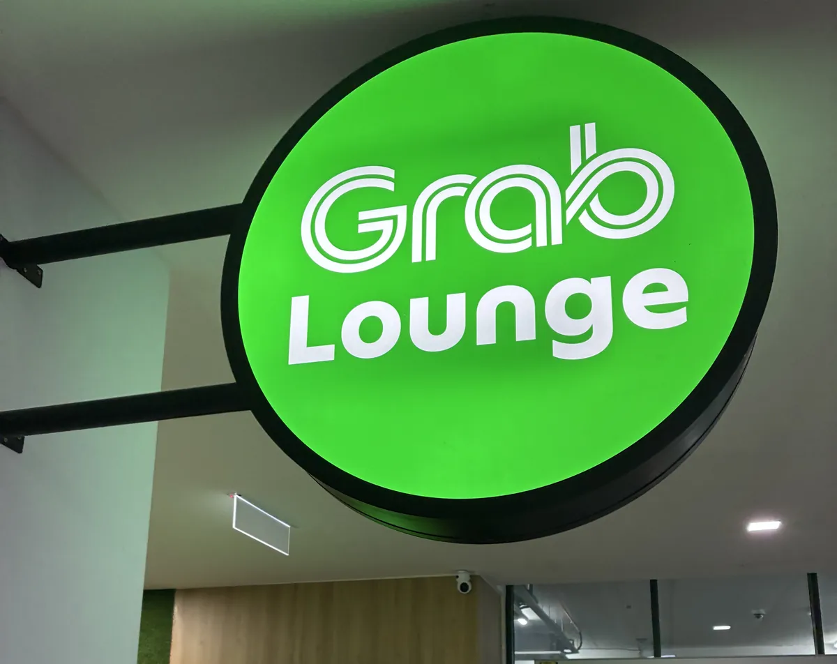 ペナン国際空港の到着階に掲げられた緑色の丸い「Grab Lounge」の照明看板
