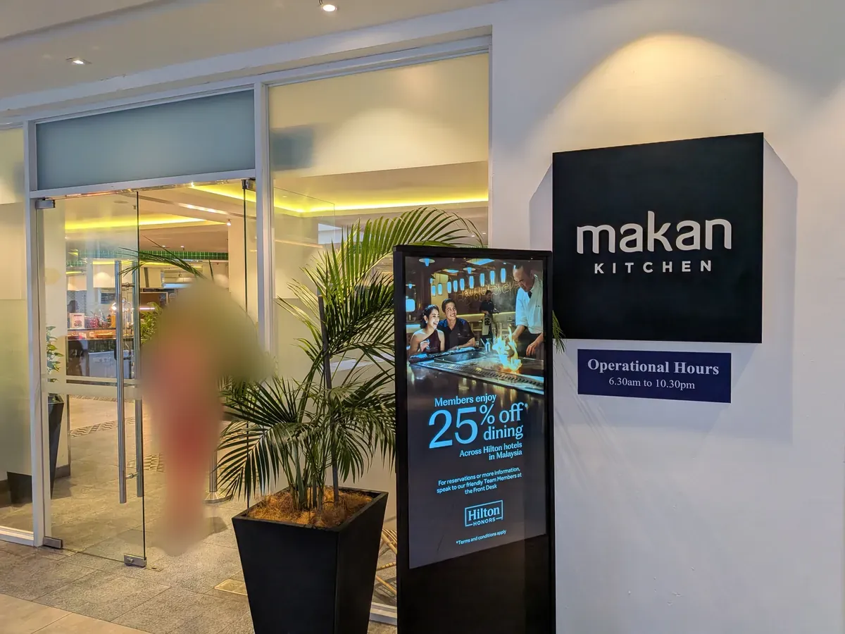 makan KITCHENの入口。ロゴサインと営業時間の案内モニター