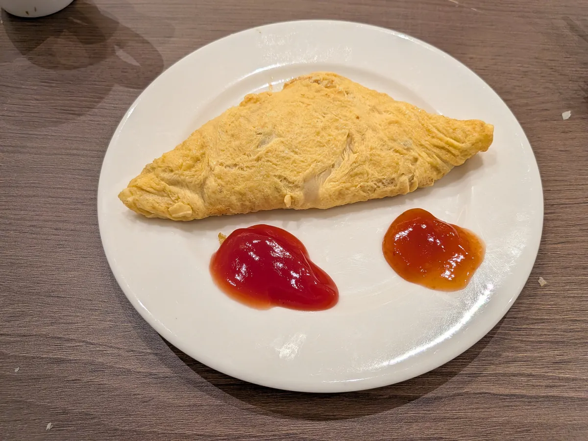 焼きたてのオムレツ。ケチャップとチリソースが添えられている