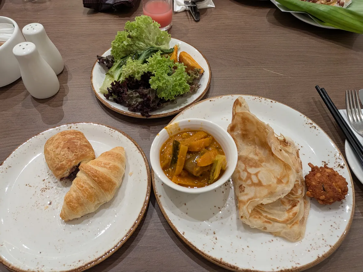 朝食のプレート。クロワッサン、カレー、ロティチャナイ、サラダ