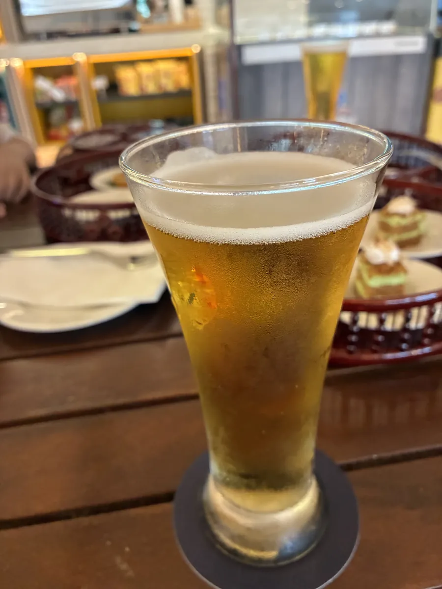 グラスに注がれた生ビールと、奥の籠のおつまみ