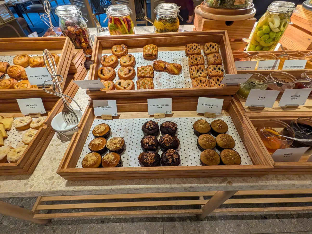 ペストリーのコーナー。クロワッサンやマフィン、チョコレート菓子が木のトレイに並ぶ