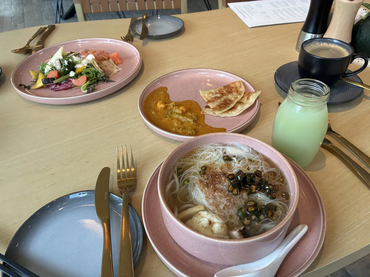 朝食のテーブル。麺のスープとサラダ、グリーンのドリンクが並ぶ