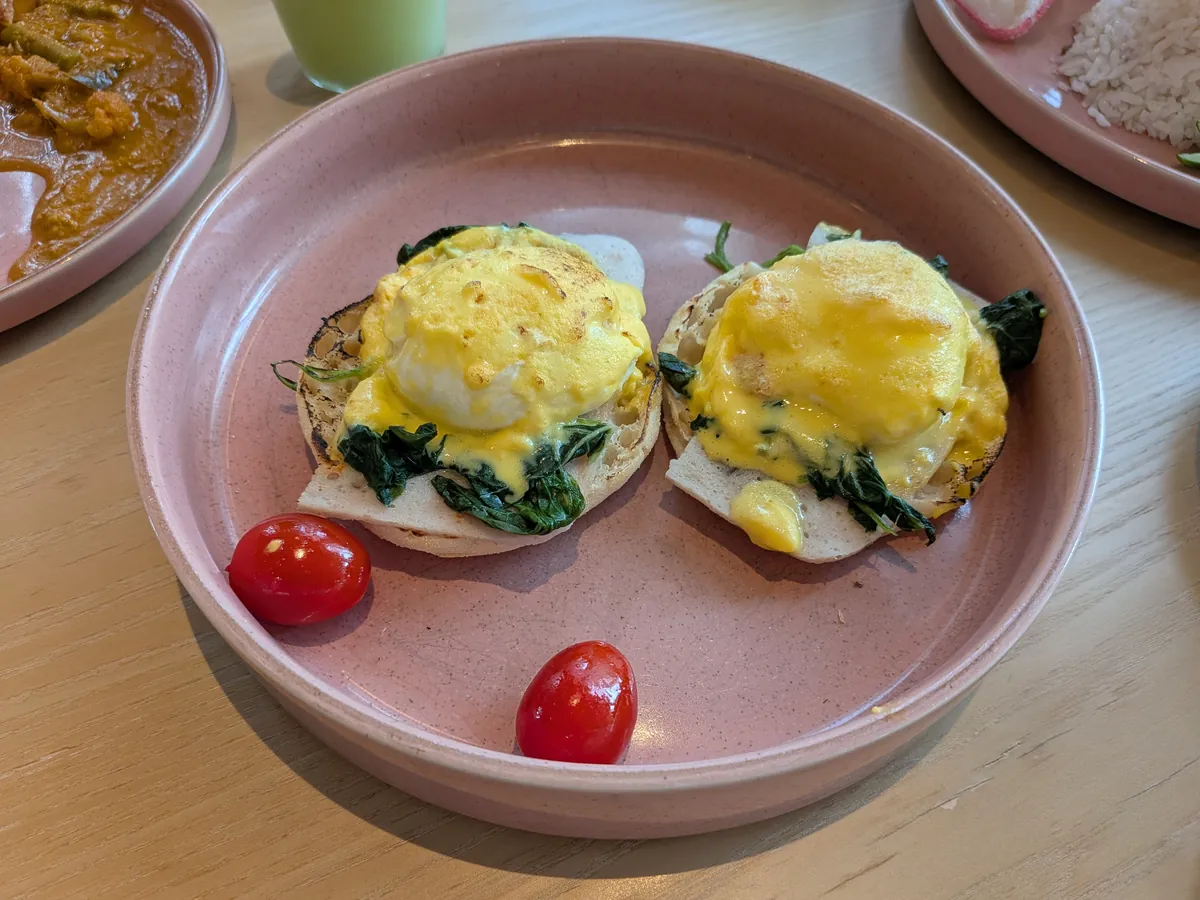 エッグベネディクト2個。ホランデーズソースがかかりミニトマトが添えられている