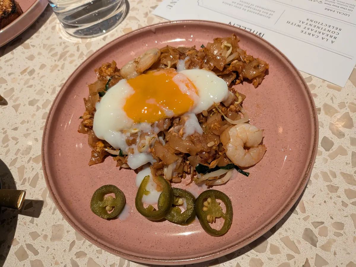 炒飯に半熟卵をのせた一皿。青唐辛子の輪切りが添えられている