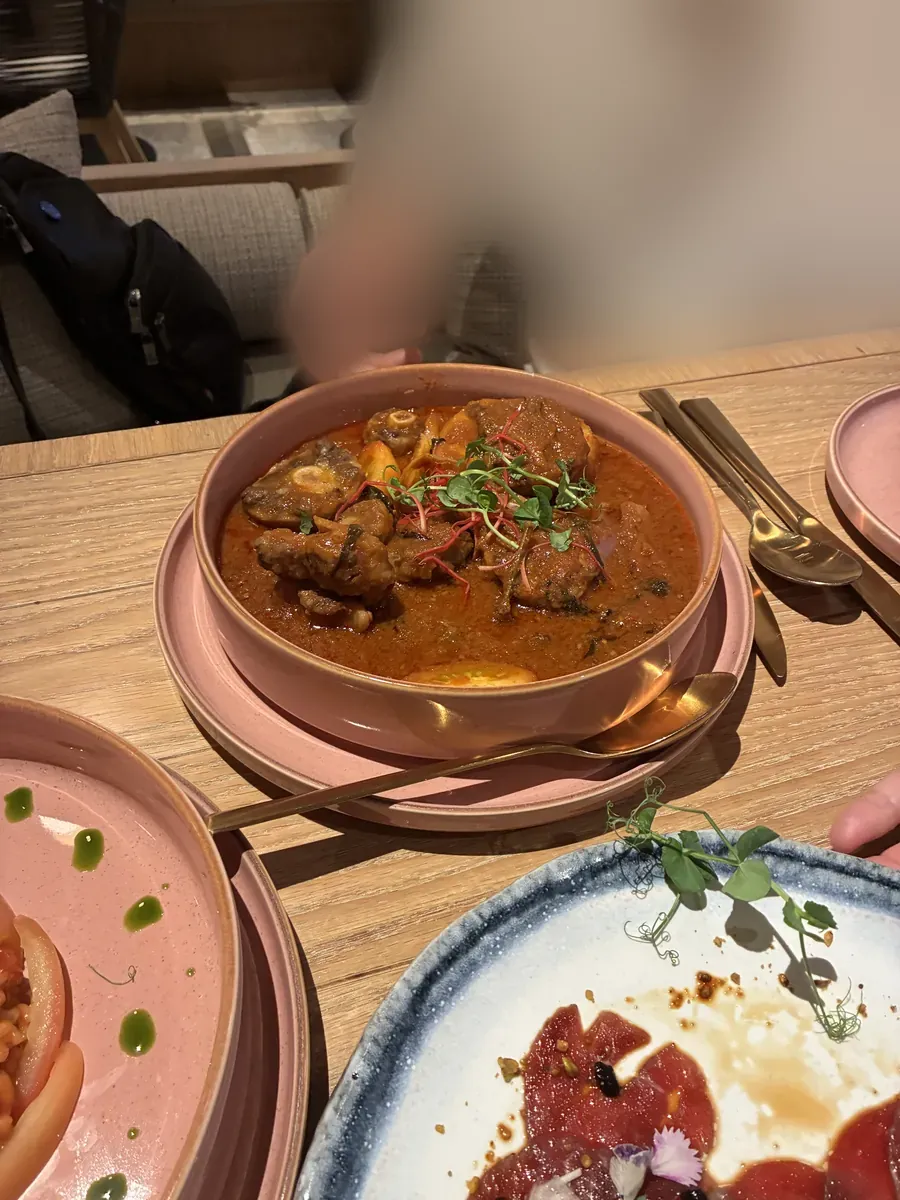 骨付き肉を煮込んだカレー。テーブルにはカルパッチョとリゾットも並ぶ