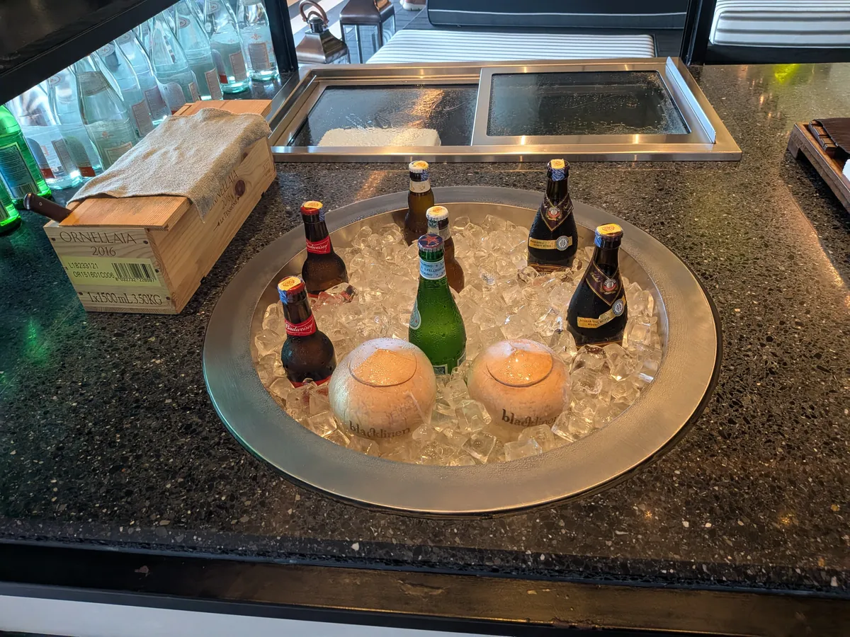 プールサイドの売店。氷を敷いたトレイに冷えたビール瓶とワインボトル、キャンドルが並ぶ