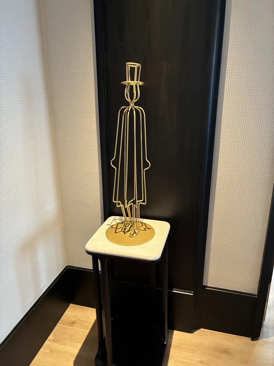 黒い壁面に飾られた金色の人物モチーフのアートと台座
