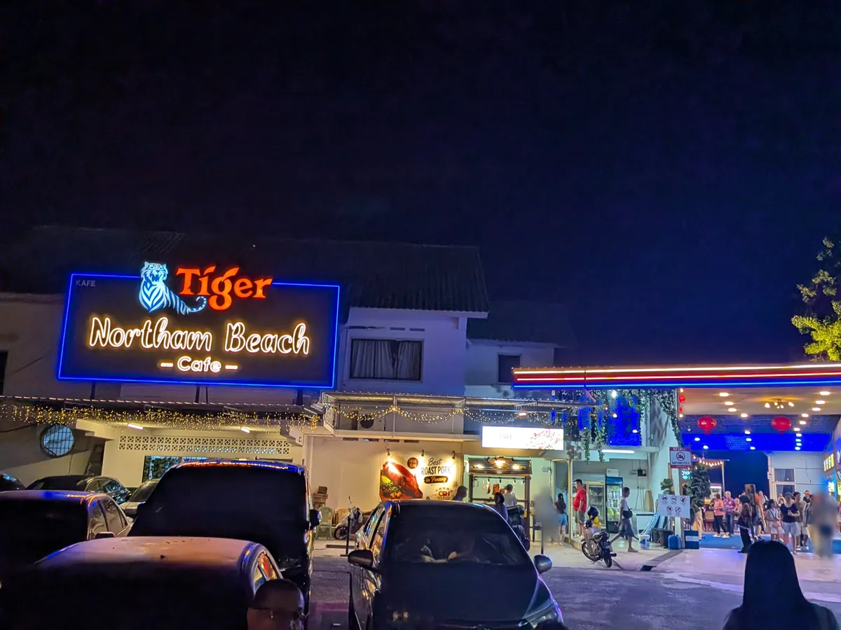 夜のノーザン・ビーチ・カフェ。青く光るTiger Northam Beach Cafeのネオン看板と駐車場