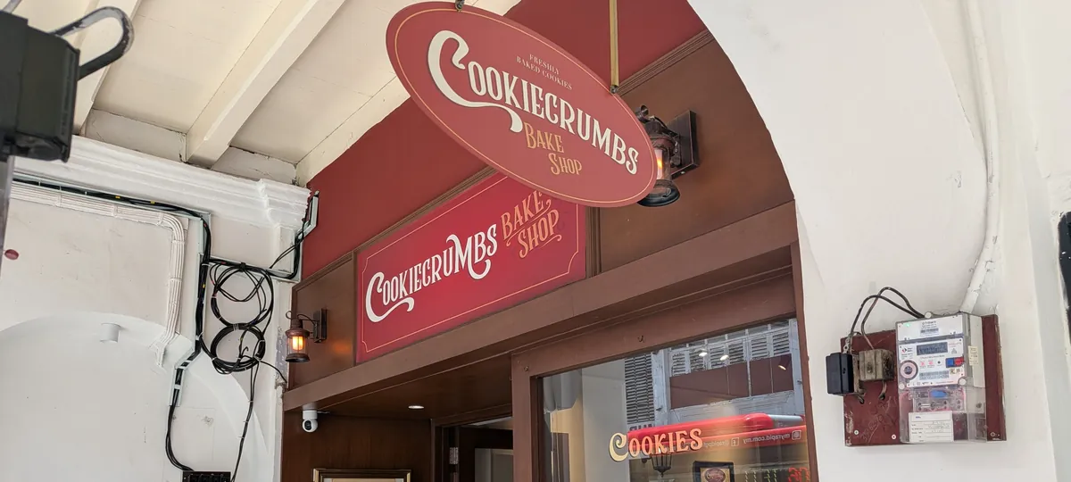 CookieCrumbs Bake Shopの店頭。赤いオーバル看板と店名の看板が並び、ショーウィンドウにCOOKIESの文字が見える