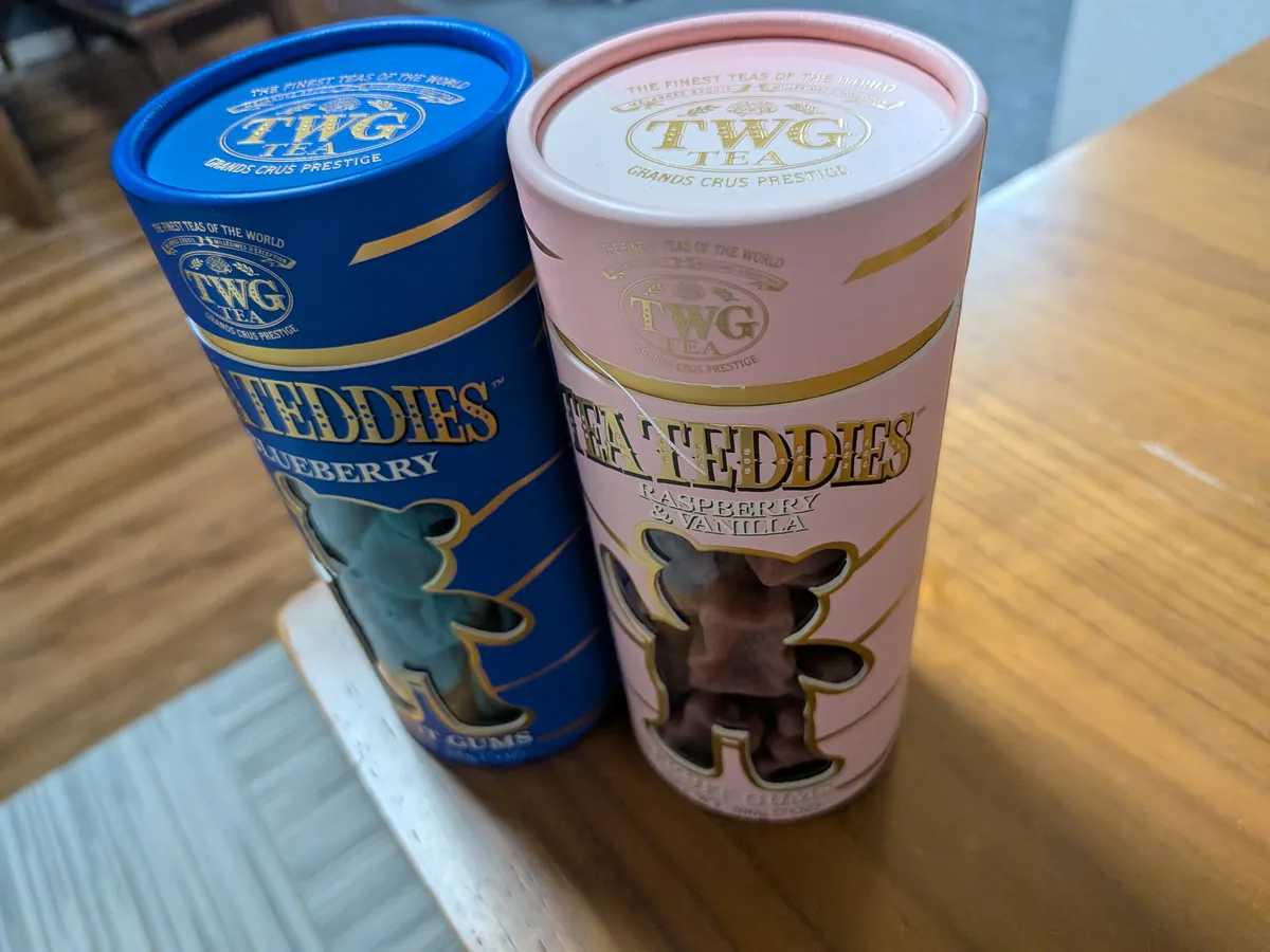 TWG Tea の『TEA TEDDIES』の筒2本。青がブルーベリー、ピンクがラズベリー＆バニラで、窓からクマ型のグミが見える
