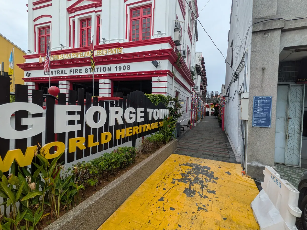 ジョージタウンの世界遺産サインと1908年築の中央消防署。赤白のコロニアル建築の前にGEORGE TOWN WORLD HERITAGE SITEの立体文字が並ぶ