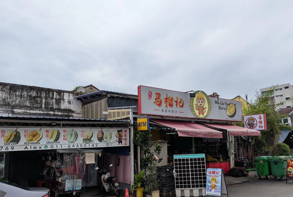 ジョージタウンのドリアン専門店。看板にドリアンの品種名が並び、店先に実が積まれている