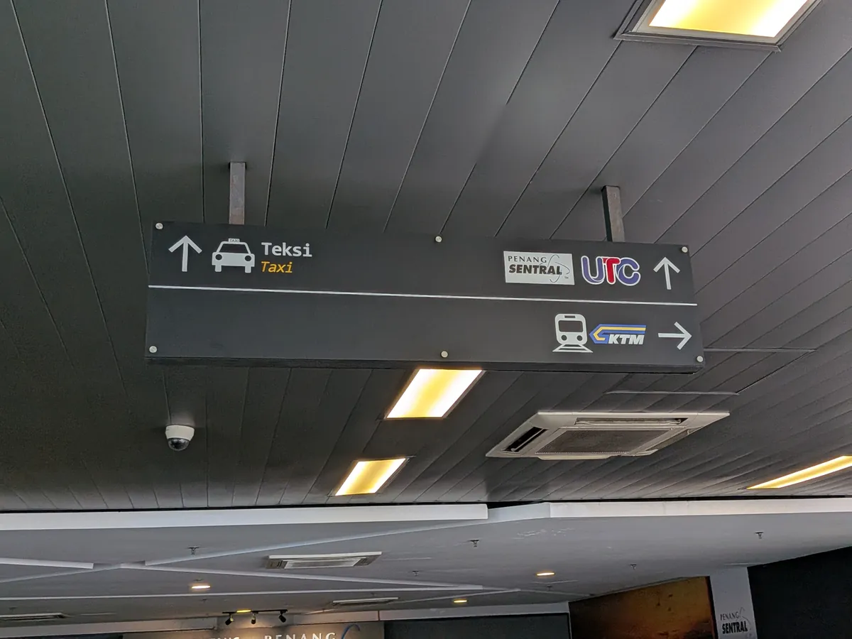 フェリーターミナルの吊り案内板。タクシーは直進、Penang SentralとKTMは右を示す矢印