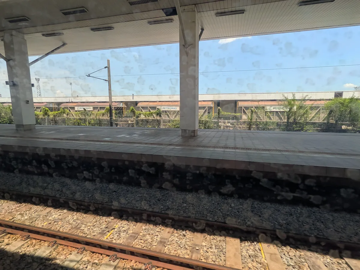 ETSの車窓から見た途中駅。奥にタンク貨車が並ぶ貨物ヤードと青空