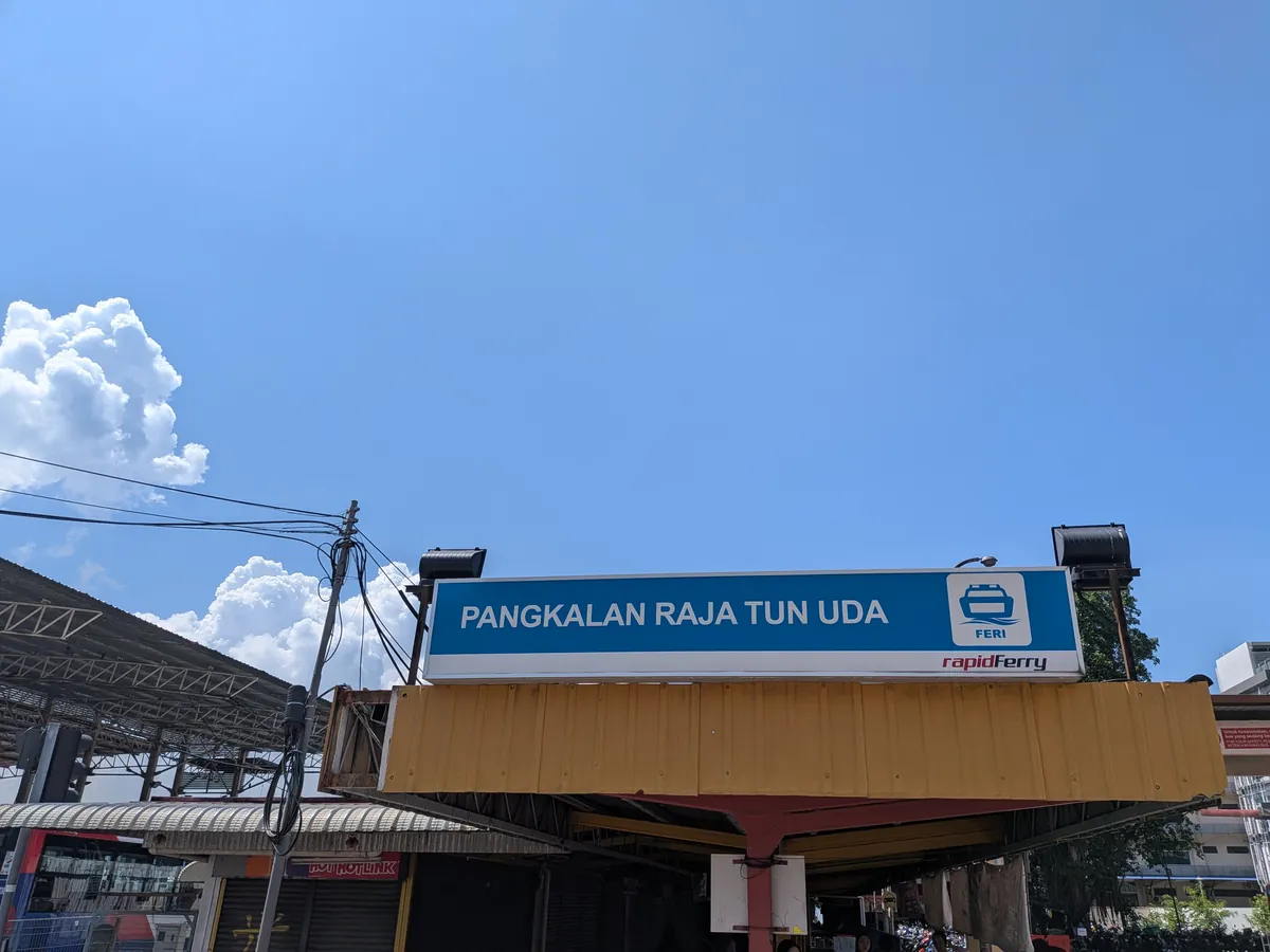 ジョージタウンのフェリーターミナル「PANGKALAN RAJA TUN UDA」の青い看板とrapidFerryのロゴ