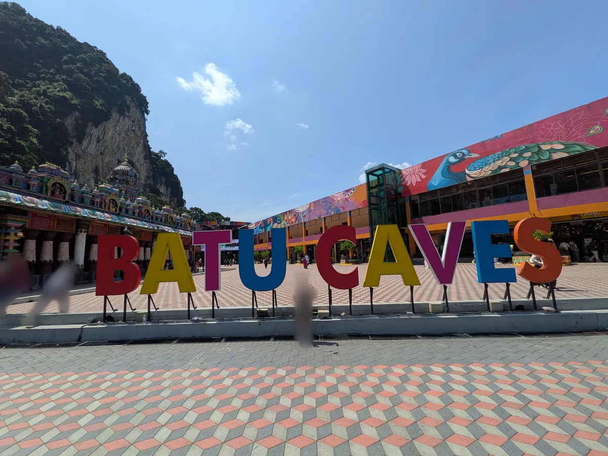 バトゥ洞窟の広場に置かれたカラフルな「BATU CAVES」のサインオブジェ