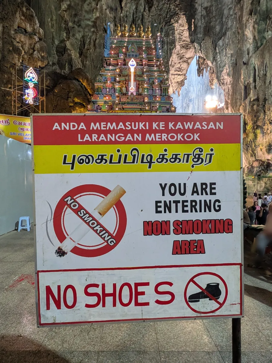 洞窟の奥にある寺院区画の手前に立つ「NO SHOES(土足禁止)」「NON SMOKING」の3言語の掲示