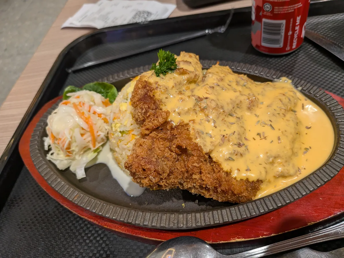焼き飯の上にチキンチョップとチーズソースがかかったシズリング料理