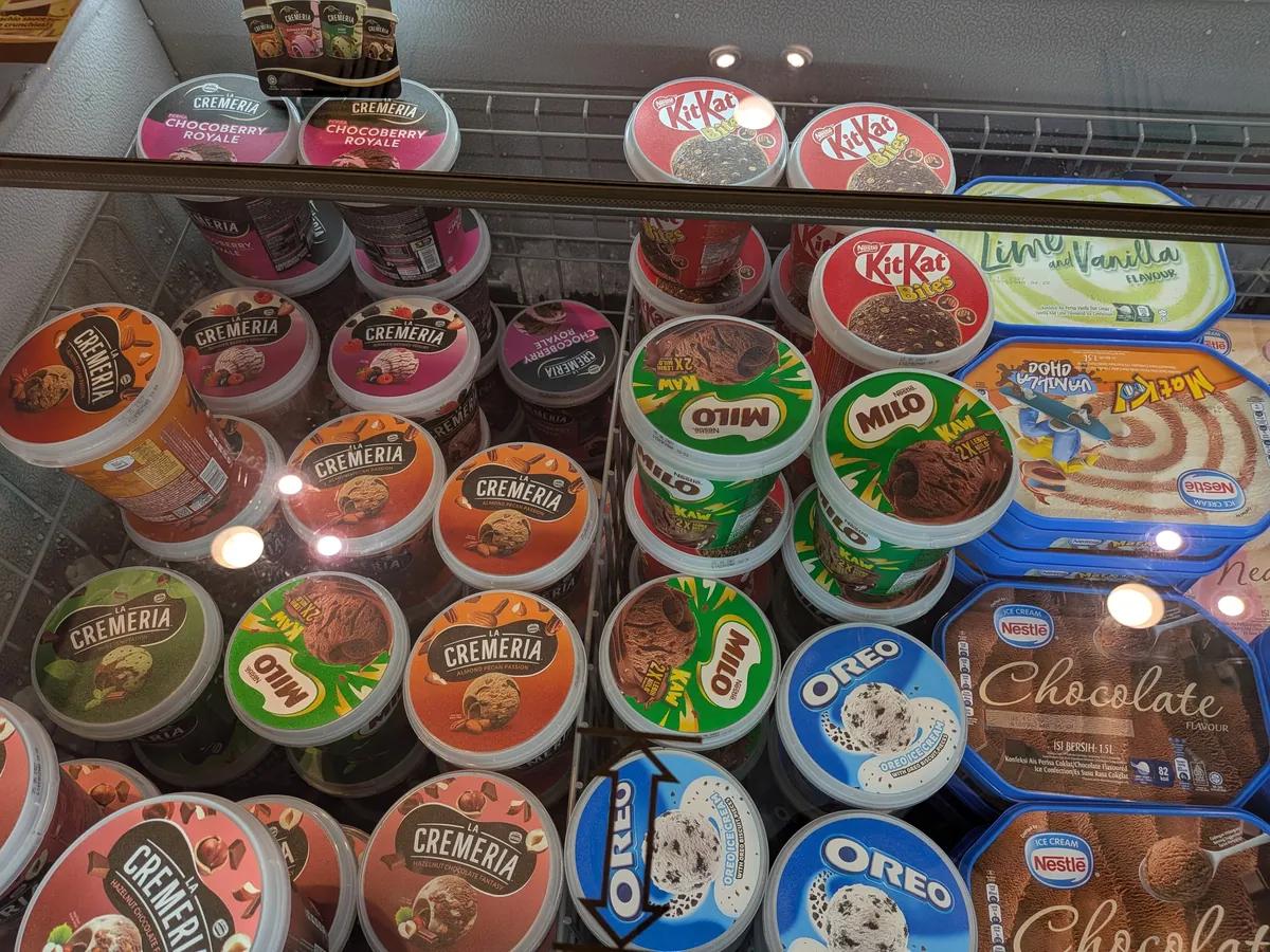ミロ味やキットカット味などのカップアイスが並ぶスーパーの冷凍庫