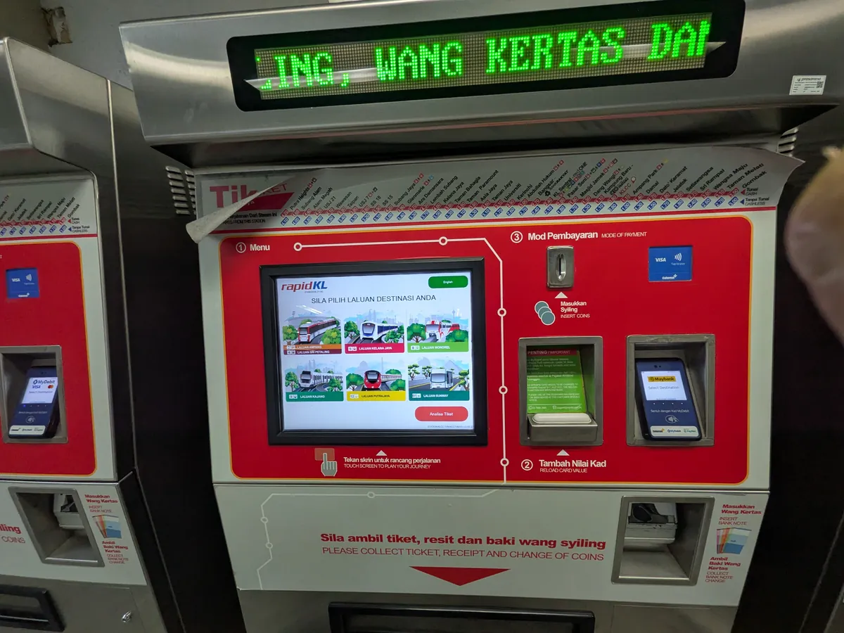 駅の赤い券売機(TVM)の全景。上部に緑のLED案内が流れる