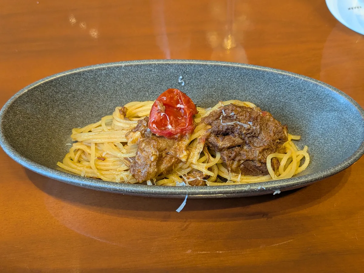 牛肉と玉ねぎの煮込みソースのスパゲッティ。セミドライトマトとチーズ添え