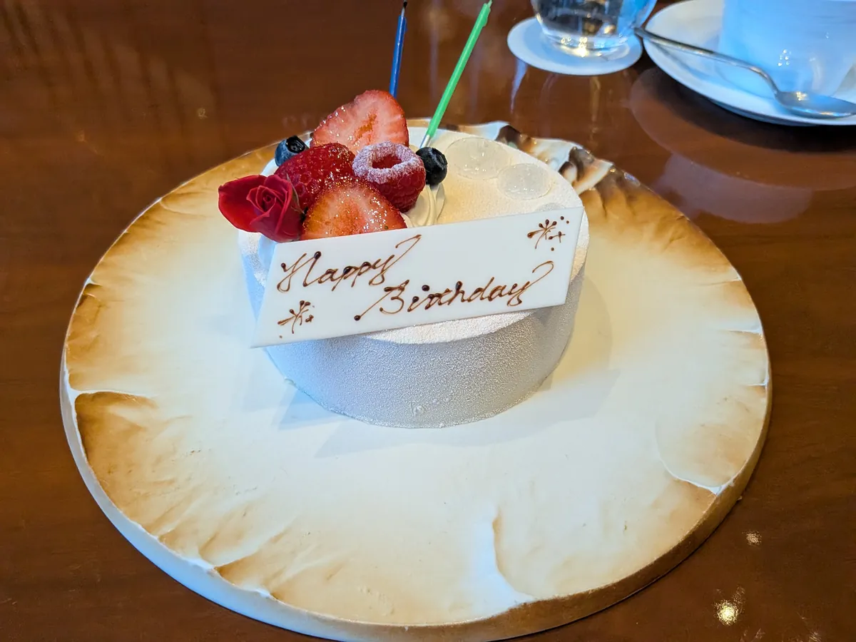 Happy Birthdayのチョコプレートとろうそくが添えられたホールケーキ