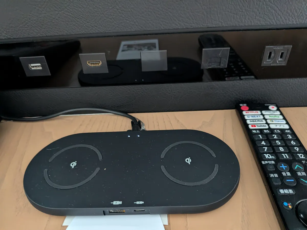 ベッドサイドのワイヤレス充電パッドとテレビリモコン、コンセント